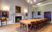 A grand council room with a historical boardroom table. 