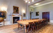 A grand council room with a historical boardroom table. 