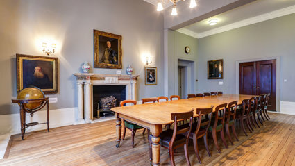 A grand council room with a historical boardroom table.