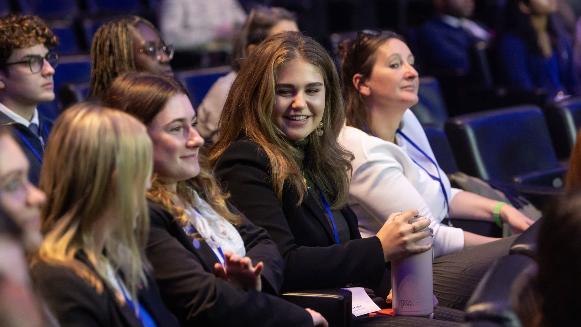 A group of young students sitting in a dark lecture hall.