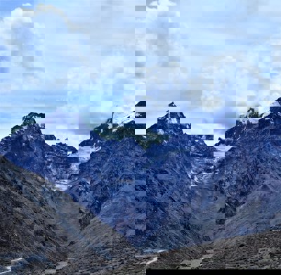 Snow covered mountain under blue cloudy sky