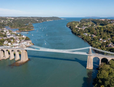 Aerial view of the Menai bridge above large blue strait.