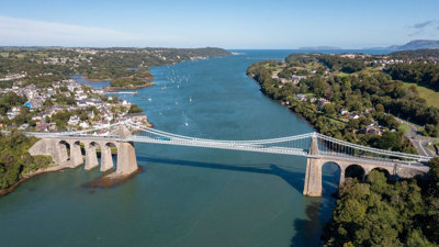 Aerial view of the Menai bridge above large blue strait.