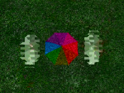 Rainbow coloured umbrella on green grass