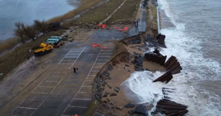 Section of a road broken after coastal damage seen from above.