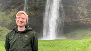 Paul Logue posing in front of a large waterfall.