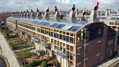 Modern houses with solar panels and gardens seen from the sky.