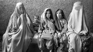 Three Afghan children between two Afgan women who are covered up.