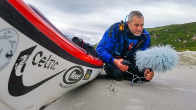 Roland lying on a beach, with photography equipment.