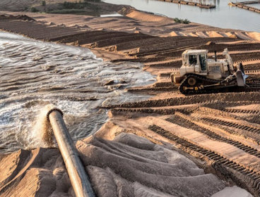 Water being pumped from a river whilst sand is removed by a digger.