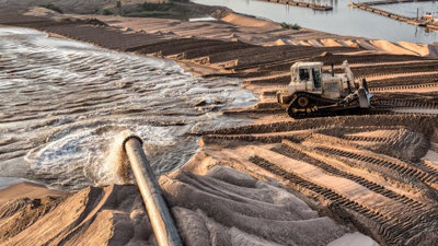 Water being pumped from a river whilst sand is removed by a digger.