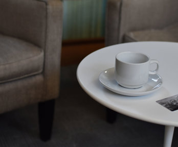 A coffee table with a cup and saucer and a card that says Royal Geographical Society.