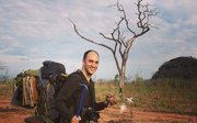 Alexandre Antonelli In Mozambique on field trip, holding a clump of earth and a flower.