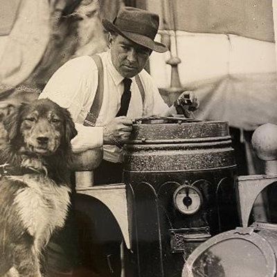 Shackleton is pictured in sepia with a dog. Both look to be on a ship as sails are in the background