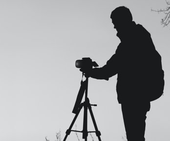 Person outside setting up a camera on a tripod