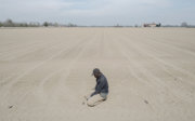 A man kneeling on a barren farming plot.