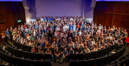 Group photo of RGS Explore 2024 attendees on the stage of the Ondaatje Theatre.