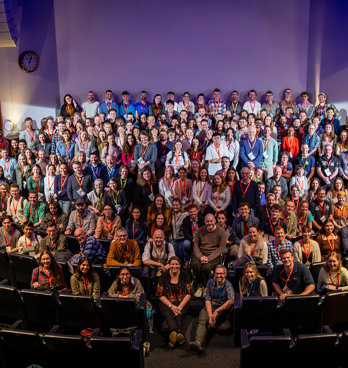 Group photo of RGS Explore 2024 attendees on the stage of the Ondaatje Theatre.