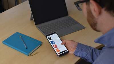 Man sat at desk looking at a mobile phone showing the Society's journal web page