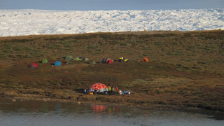 A group of tents next to a river in the wilderness of Iceland.