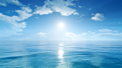 Blue ocean against backdrop of blue sky and a sun shining on the horizon.