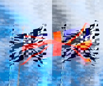 A union jack flag flying in the wind on a blue sky background