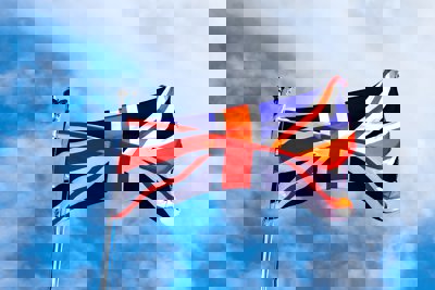 A union jack flag flying in the wind on a blue sky background