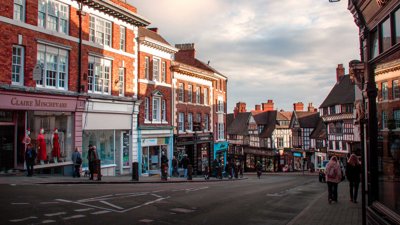 A shopping high street showing shops and people.