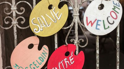 Wooden signs hanging from a metal gate.