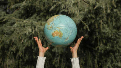 Hands throwing a globe into the air.