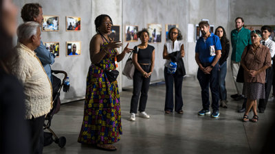 Anne Nwakalor speaking to a group of people in a modern art exhibition space.