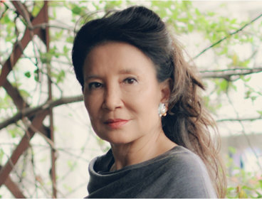 Headshot of author Jung Chan against backdrop of plants. 