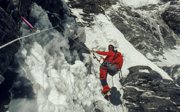 Expeditioner in winter gear climbing a snow and ice covered mountain.