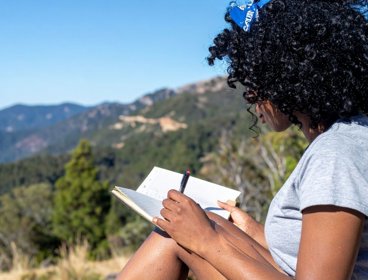 Person writing in notebook outside.