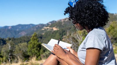 Person writing in notebook outside.