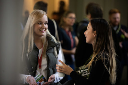 Two people at a conference smiling whilst engaged in a lively conversation.