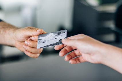 Close up of a Society membership card being passed from one person's hand to another's.