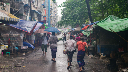 People walk through an informal market settlment whist its rains