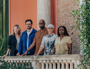 Five people standing next to a stone balcony balustrade.