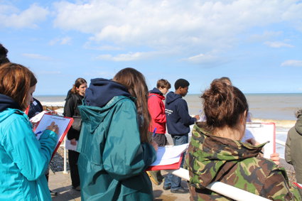People standing by the sea holding clipboards and making notes