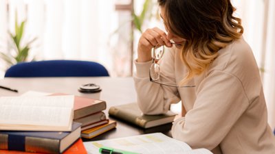 Woman sat looking down at books on a table