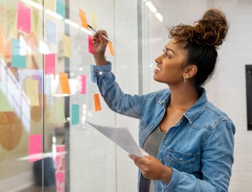 Person writing notes on glass board.