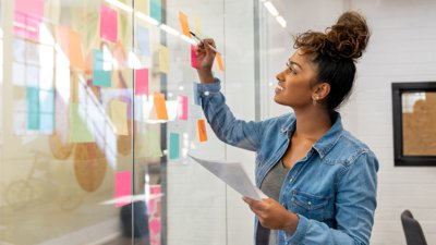 Person writing notes on glass board.