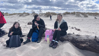 Students on a beach eating lunch during a break in their fieldwork.