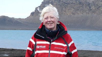 Anne Strathie posing for a photo in front of the natural harbour on Deception Island.