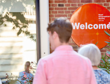 People walking into the Society building with welcome sign in background.