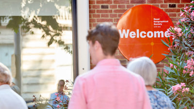 People walking into the Society building with welcome sign in background.