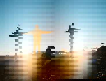 Person standing on a hill with arms outstretched