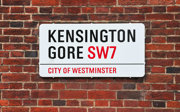 A street sign on a brick wall that says Kensington Gore SW7 City of Westminster.