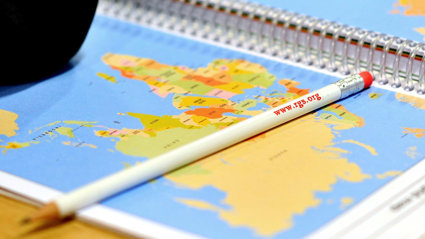 Close up of a pencil with the rgs website printed on it laying on a map.